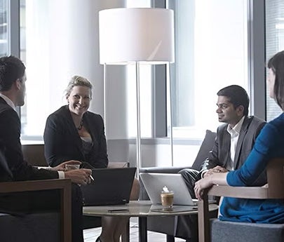 A group of professionals in business attire having a discussion in a modern office setting.