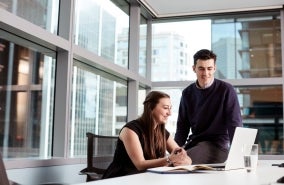 Two coworkers in a discussion in front of a laptop.