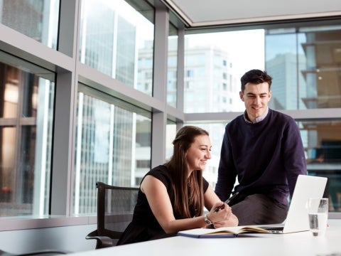 Two coworkers in a discussion in front of a laptop.